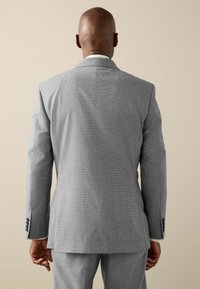 Grau strukturierte Sakkojacke mit Reverskragen, einfacher Schlitze und Knopfdetails mit drei Knöpfen an den Ärmeln. Die Rückansicht zeigt eine taillierte Passform und einen glatten Stoff.