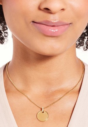 Collier en ton or avec un pendentif rond présentant une surface lisse et une accent scintillant, reposant sur une chaîne délicate.