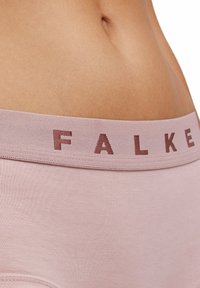 Helle rosa Unterwäsche mit einem weichen Bund, in dem der Markenname "FALKE" in einem dunkleren Rosa gestickt ist. Glatte Textur, schlichtes Design.