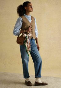 Pruunist ruudustikku vest kergelt sinise pluusi peal, koos lahtiste siniste teksadega. Helepruun käekott koos mustrilise siidist salli aktsendiga. Pruunid loaferid.