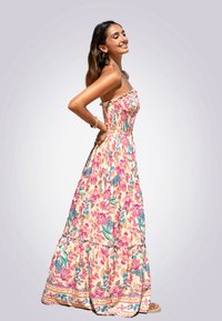 Blumenkleid im Maxiformat mit trägerlosem Design, einem gerafften Oberteil und bunten Mustern in Pink, Blau und Grün auf einem hellen Hintergrund.