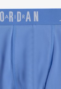 Lyseblå herreboxershorts med en blød tekstur, der har en grå elastik med "JORDAN" skrevet med fede bogstaver.