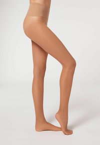 Medias nude transparentes con un acabado suave, cinturilla alta y un aspecto de tono de piel natural, con una banda superior ligeramente texturizada.