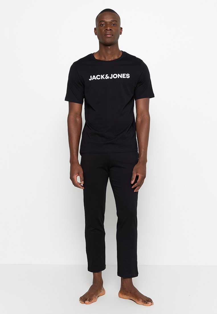 Camiseta de algodón negra con "JACK&JONES" impreso en blanco, combinada con pantalones de algodón negros a juego, ambos con un diseño simple y ajustado.