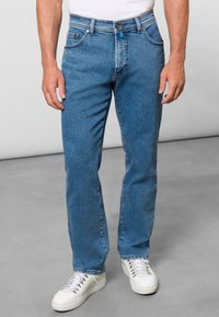 Jasnoniebieskie dżinsy o prostym kroju, z pięcioma kieszeniami i widocznymi szwami. W połączeniu z białymi trampkami.