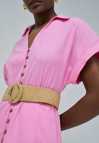 Rosa Hemdblusenkleid mit Kragen, kurzen Ärmeln und einem geflochtenen Strohgürtel. Verfügt über Holzknöpfe an der Vorderseite und einen strukturierten Stoff.
