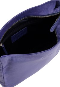 Lilla lædertaske med en struktureret overflade. Har en guldlås, sort stofforing og en indvendig lomme. Minimalistisk design uden forskønnelse.