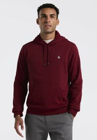 Bordeaux hoodie van zacht materiaal met een voorzak, verstelbare trekkoordcapuchon en klein geborduurd logo op de linkerborst.