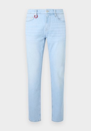 Svijetloplave traperice ravnog kroja s prednjim džepovima, petljama za pojas, kopčanjem na tipku i malim crvenim privjeskom za ključeve pričvršćenim na lijevu petlju za pojas.