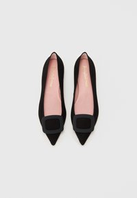 Melni zamšaini plakano zābaki ar norādītu pirkstu dizainu, ar lielu melnu kvadrātveida sprādzi priekšā un mīkstu rozā iekšējo odere.