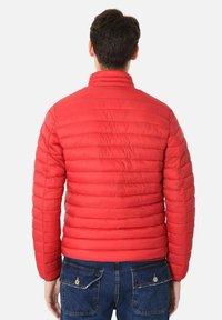 Giacca imbottita rossa con colletto alto, cuciture orizzontali e polsini elastici. La parte posteriore presenta una texture liscia e una silhouette aderente.