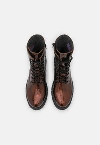 Bottines en cuir verni marron avec lacets noirs, doublure en feutre texturé et semelle noire robuste. Dotées d'une fermeture éclair latérale pour un enfilage facile.