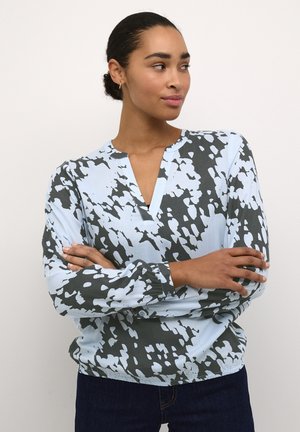 Langsleeve blouse in lichtblauw en donkergroen met een abstract patroon. Heeft een v-halslijn en geplooide polsmanchetten.