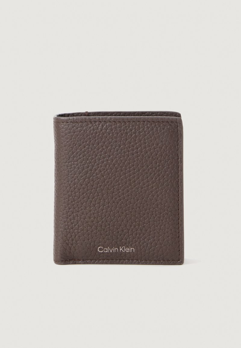 Billetera de cuero marrón con textura y diseño plegable, con un logotipo de marca visible en la parte frontal inferior. Bordes suaves y forma compacta.