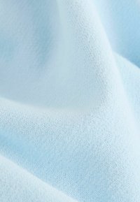 Tessuto a maglia azzurro chiaro con una consistenza morbida e una trama fine, caratterizzato da una superficie liscia ed uniforme senza modelli o accenti visibili.