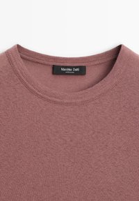 Rippenshirt mit kurzen Ärmeln und Rundhalsausschnitt aus weichem Mauve-Stoff. Mit einem schwarzen Etikett mit "Massimo Dutti" und Pflegehinweisen im Kragen.
