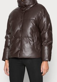 Brązowa pikowana skórzana kurtka z wysokim kołnierzem, zatrzaskami i bocznymi kieszeniami. Materiał ma gładkie, błyszczące wykończenie i prosty krój.