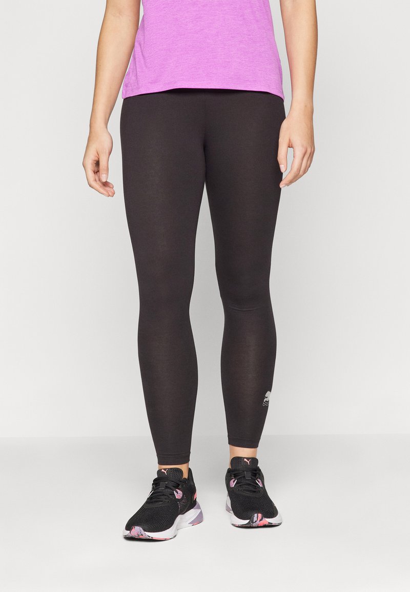Svarta leggings i stretchigt material, åtsittande design, med en logo på underbenet. Kombinerat med en rosa t-shirt och svarta löparskor.