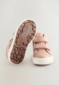 Chaussures en cuir roses avec deux bandes Velcro, dotées d'une semelle en caoutchouc texturé avec un design de licorne et des accents étoilés.