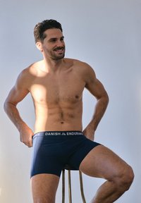 Boxer para hombre de color azul marino con una cintura elástica negra con la marca. La tela parece suave con una silueta ajustada, mostrando una textura lisa.