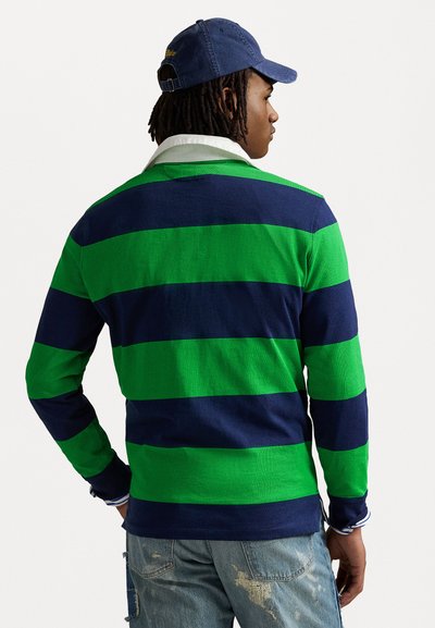 Long-sleeve polo shirt with green and navy horizontal stripes, white collar, and blue cap. Worn with distressed blue jeans.