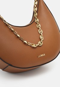 Sac à main en cuir texturé marron avec des bords noirs, une bandoulière en chaîne dorée et un petit logo de marque doré à l'avant.