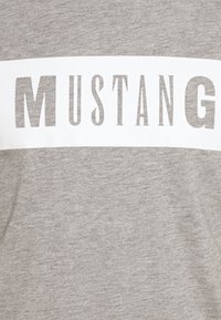 Szary sweatshirt z wyraźnym białym napisem "MUSTANG". Wykonany z miękkiego materiału o gładkiej fakturze, z okrągłym dekoltem.