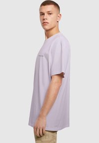 Lyse lilla kortærmet t-shirt med rund hals og afslappet pasform. Har diskret logodetalje på brystet. Glat bomuldsstruktur.