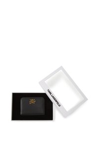 Zwarte leren portemonnee met gouden logo op de voorkant, geplaatst in een zwarte fluwelen doos. De doos is wit met "KARL LAGERFELD" gedrukt op de rand.