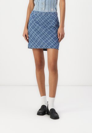 Denim miniskjørt i et blått rutemønster, med frontlommer, en tettsittende livlinje og rett snitt. Kombinert med svarte loafers og hvite sokker.