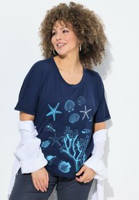 Námořnická modrá tričko s krátkým rukávem má design mušle a korálu v světlé modré barvě. Měkká, lehká tkanina s volným střihem.