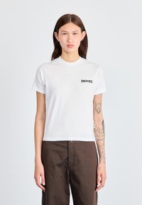 Bílá bavlněná tričko s kulatým výstřihem a krátkými rukávy. Na levém prsu se nachází černé logo "DICKIES". Hladká textura.