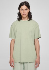 Svetlozelené oversized tričko s krátkymi rukávmi, okrúhlym výstrihom a jemnou textúrou, vyrobené z mäkkej bavlnenej látky.