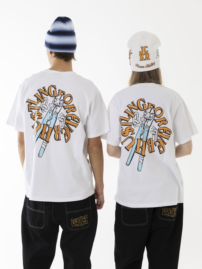 Weiße Baumwoll-T-Shirts mit bunten Grafikdrucken auf dem Rücken, kombiniert mit schwarzen, weiten Hosen. Die Accessoires umfassen eine weiß-blau gestreifte Mütze.