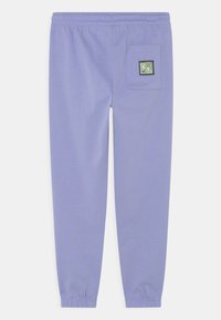 Calças de moletom roxas com cintura elástica, punhos afunilados e um bolso traseiro com um rótulo colorido. Material de algodão suave.