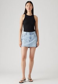 Svart ribbet tank topp kombinert med lys blå denim miniskjørt. Skjørtet har frontlukking og to frontlommer. Svarte hælsandaler.