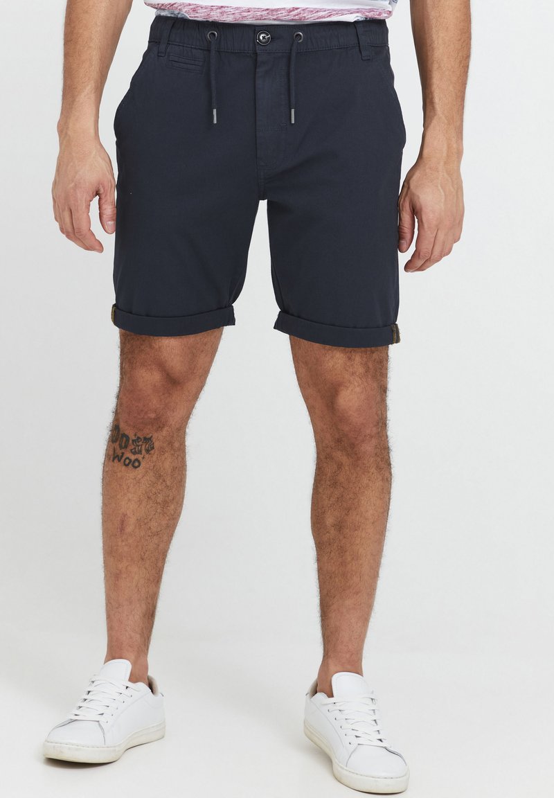 Pantaloni corti blu navy con risvolti, vita con lacci e tasche frontali. Realizzati in tessuto leggero, adatti per un abbigliamento casual.