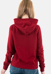 Sudadera roja con capucha ajustable, puños acanalados y dobladillo. Tejido suave con una textura lisa, vista desde la parte posterior. Diseño casual.