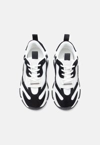 Baskets texturées noir et blanc en mesh et suède, dotées d'une semelle épaisse et d'éléments de design contrastants.