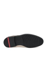 Suela de goma negra con agarre texturizado, con un acento rojo en el talón. Parte inferior suave con un patrón de banda definido.