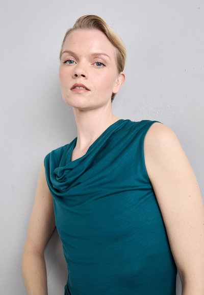 Teal ermeløs topp med drapert halslinje, laget av mykt stoff. Har en jevn tekstur og en tettsittende silhuett.