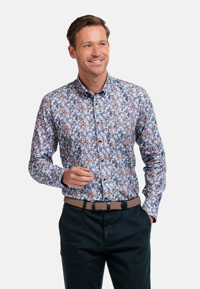 Chemise à boutons florale en bleu, marron et blanc ; munie de manches longues et d'un col. Assortie à un pantalon sombre et une ceinture tissée.