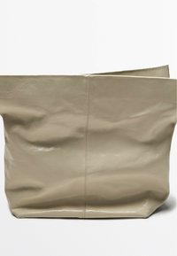 Beige faux leather tote bag with a matte finish, soft texture, and an unstructured design. Features a central seam and no visible hardware.