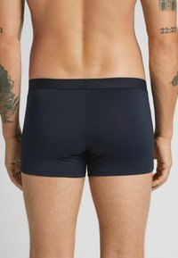 Námořnické modré boxerské kraťasy z hladké látky s měkkým elastickým pasem. Mají přizpůsobený střih, minimalistický styl a žádné viditelné vzory.