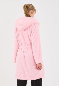 Rosa Kapuzenrobe aus weichem, flauschigem Material mit tailliertem Gürtel und zwei Taschen. Mittellanges Design mit langen Ärmeln und strukturiertem Stoff.