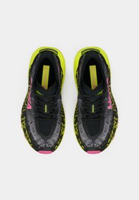 Svarta och grå mönstrade sneakers med neongröna detaljer och en ljusrosa logotyp. Har snörning och en dämpad sula.
