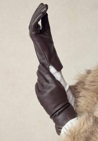 Brune læderhandsker med en tætsiddende design, der har en glat tekstur og en håndledslængde. Et lysfarvet stoffor er synligt.