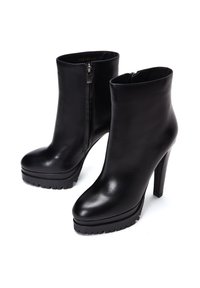 Botas de tobillo de cuero negro con punta redonda, tacón alto en bloque, cierre de cremallera y suela resaltada con dibujo para mayor agarre. Textura suave y diseño elegante.