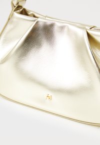 Metallic gold handbag with a smooth, reflective surface, featuring a signature logo detail and structured pleat design.