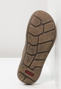 Semelle de chaussure en caoutchouc marron présentant un motif de semelle texturé ; marquage de taille "41" et logo "rieker" au niveau du talon.